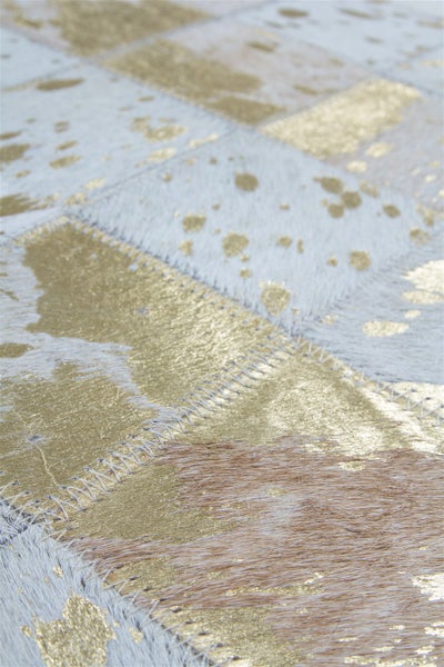 Patchwork-Teppich aus echtem Kuhfell mit goldfarbenem Metallic-Effekt und dekorativen Zickzack-Nähten.