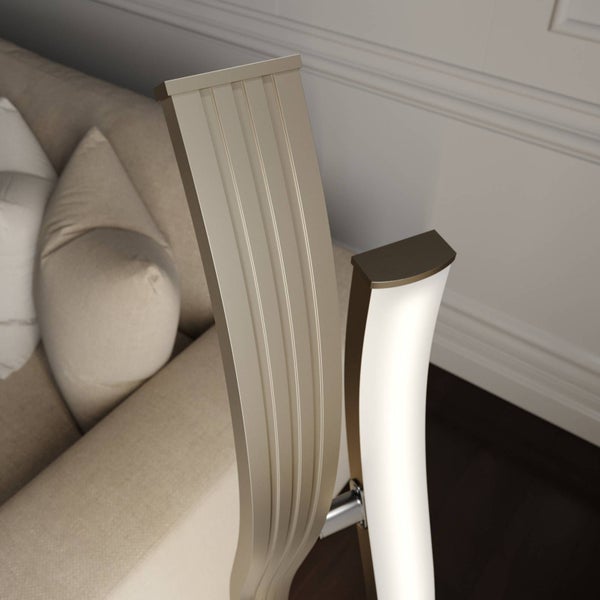 Detailaufnahme einer geschwungenen LED-Stehleuchte in Metallic-Optik neben einem hellen Sofa im Wohnzimmer.