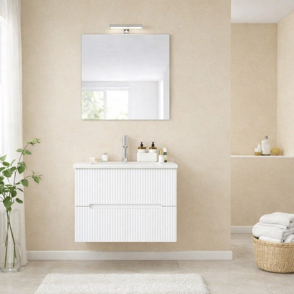 Modernes Badezimmer mit weißem Waschtischunterschrank in Rillenoptik, Aufsatzwaschbecken, Spiegel mit Leuchte und Armatur in harmonischem Wohnraum.