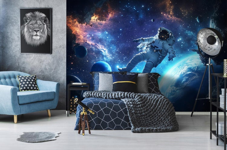 Modernes Schlafzimmer mit Weltraumtapete, blauem Sessel und dekorativen Elementen wie einem Löwenbild und einem Teleskop