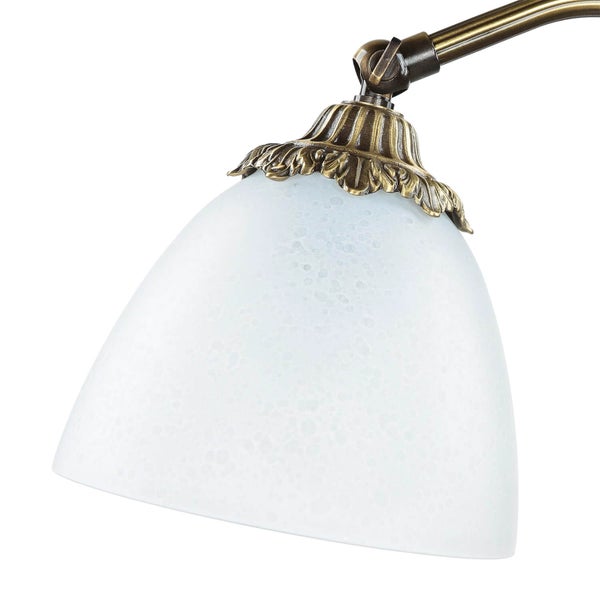 Nahaufnahme einer Lampe mit Glasschirm und Messingdetails