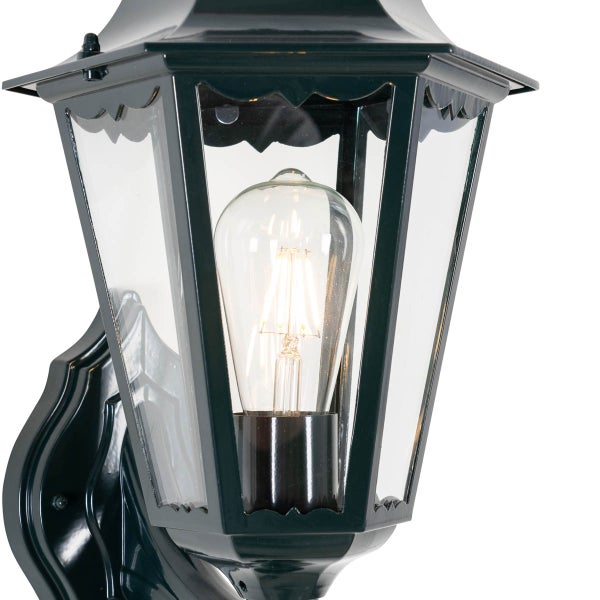 Klassische Außenwandleuchte mit Metallrahmen, Glaseinsätzen und brennendem Filament-Leuchtmittel.