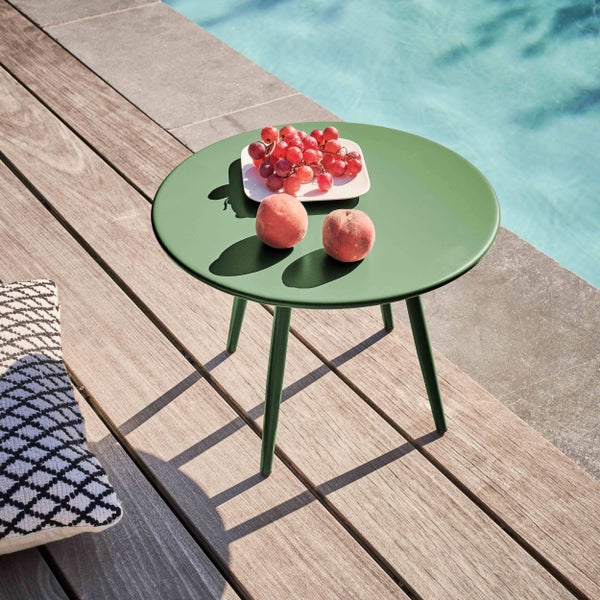 Runder grüner Beistelltisch aus Metall auf einer Holzterrasse am Pool mit Weintrauben und Pfirsichen.