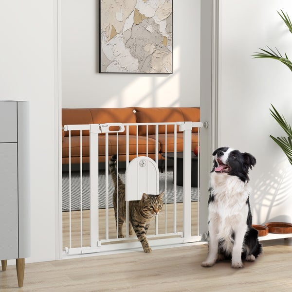 Schutzgitter für Haustiere mit integrierter Katzenklappe im Türrahmen, Katze nutzt die Öffnung, Hund sitzt daneben in einem hellen, organisierten Raum.