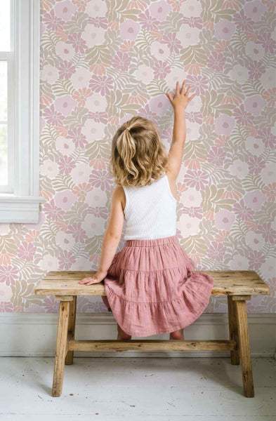 Tapete mit Retro-Blumenmuster in einem hellen Kinderzimmer, Kind sitzt auf einer rustikalen Holzbank vor der Wand.