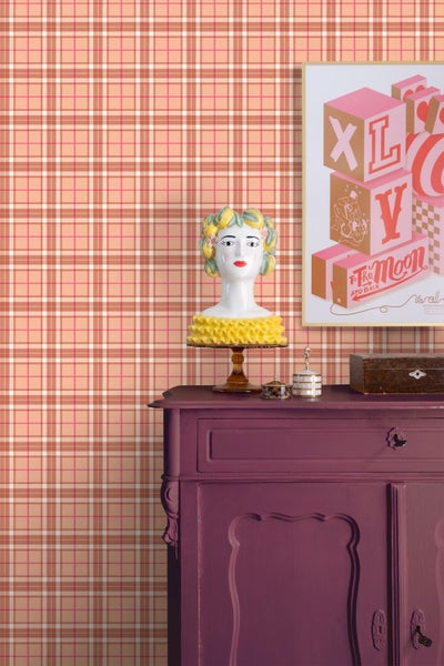 Vliestapete mit Karomuster hinter einer dunklen Kommode mit dekorativer Büste und gerahmtem Bild.