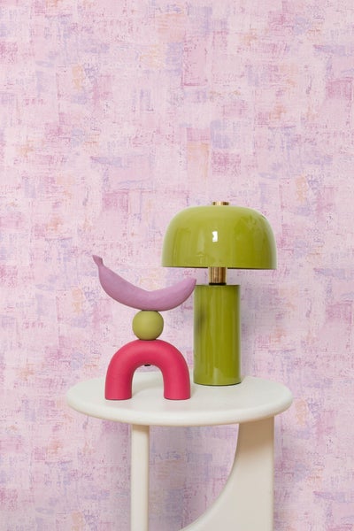 Dekorative Szene mit Lampe und Skulptur auf einem Beistelltisch vor einer gemusterten Wand