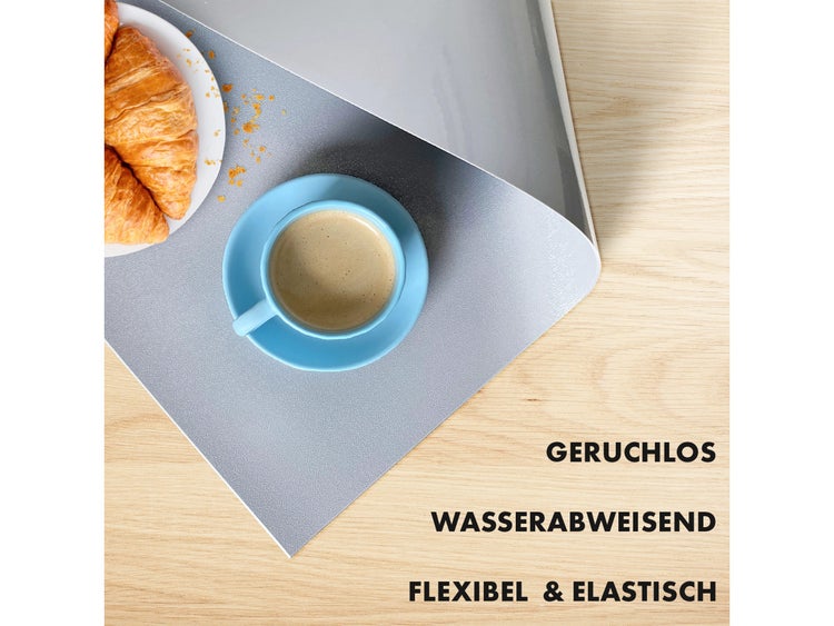 Terrassenszene mit Rattansofa, Kissen, Hocker und strukturiertem Teppich