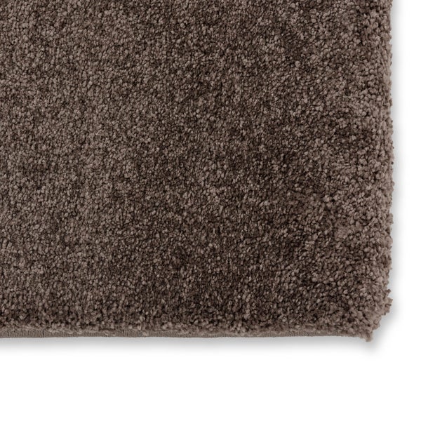 Brauner Hochflor-Teppich mit weicher, zotteliger Struktur und sichtbarer Kante.