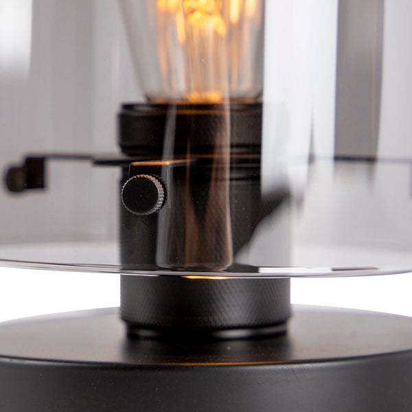 Nahaufnahme einer Tischleuchte mit transparentem Glasschirm und Drehknopf