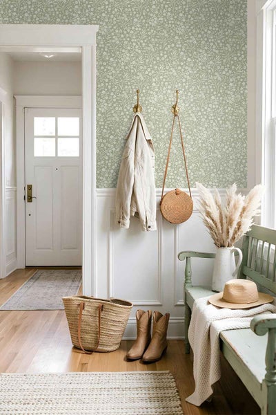 Flur mit blumiger Vliestapete, weißem Wandpaneel, Holzbank und Accessoires im Landhausstil.