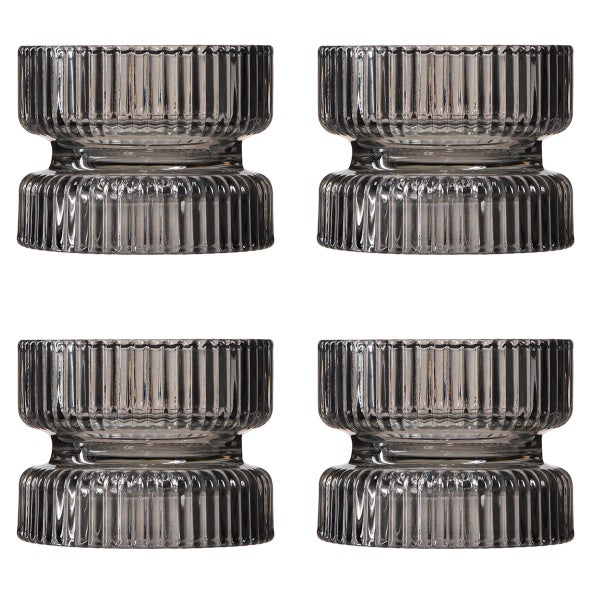 Vier gerippte Teelichthalter aus rauchgrauem Glas.