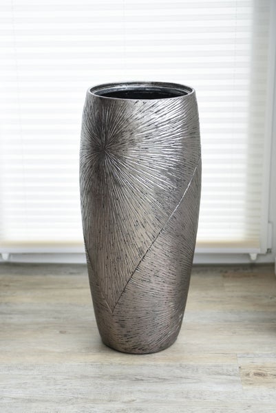 Große silberfarbene Bodenvase aus Metall mit strahlenförmiger Struktur und geometrischem Muster.