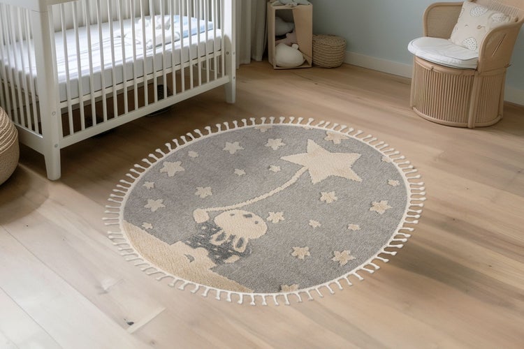 Runder Kinderteppich mit Sternenmotiv und Fransen in einem gemütlichen Kinderzimmer mit Kinderbett und Spielzeugkorb.