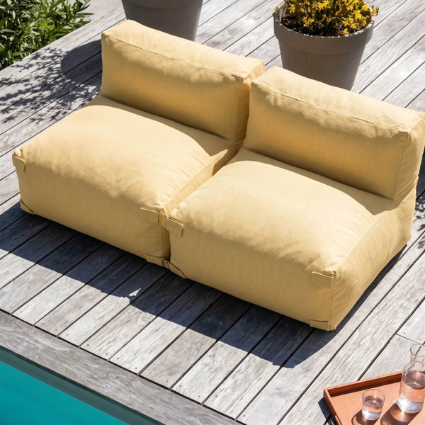 Zwei modulare Outdoor Sitzsäcke in Gelb auf einer Holzterrasse am Pool. Moderne Gartenlounge aus wetterfestem Stoff für entspannte Stunden im Freien.
