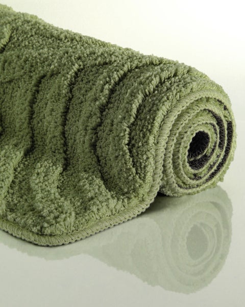 Aufgerollte grüne Badematte aus flauschigem Hochflor mit strukturierter Oberfläche.