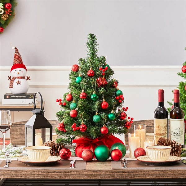 Festlich gedeckter Tisch mit kleinem Weihnachtsbaum, Kugeln, Schleife, Geschirr und Dekorationen für Weihnachten