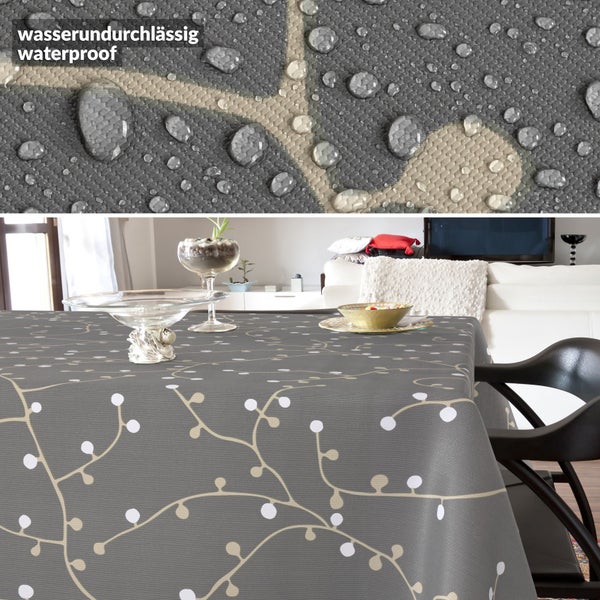 Wasserdichte Tischdecke mit Zweig- und Beerenmuster auf einem Tisch in einem hellen Wohnzimmer, Nahaufnahme der wasserabweisenden Oberfläche.