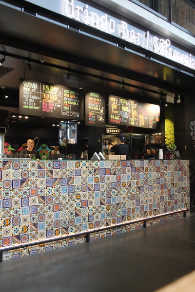 Gusseiserner Kaminofen mit Rauchrohr vor einer Wand mit Fliesen und Dekorationen