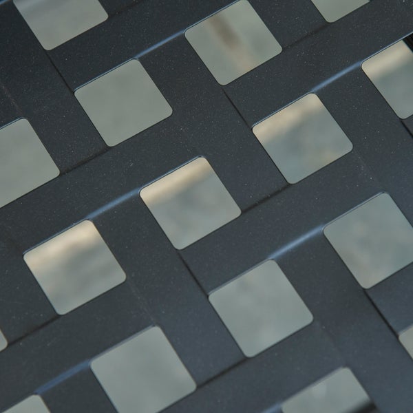 Nahaufnahme einer anthrazitfarbenen Metalloberfläche mit quadratischem Lochmuster.