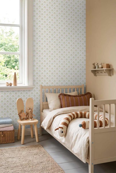 Hell gestaltetes Kinderzimmer mit einer gemusterten Vliestapete mit floralen Motiven, einem Holzbett, einem Hasen-Stuhl und einem hellen Teppich.