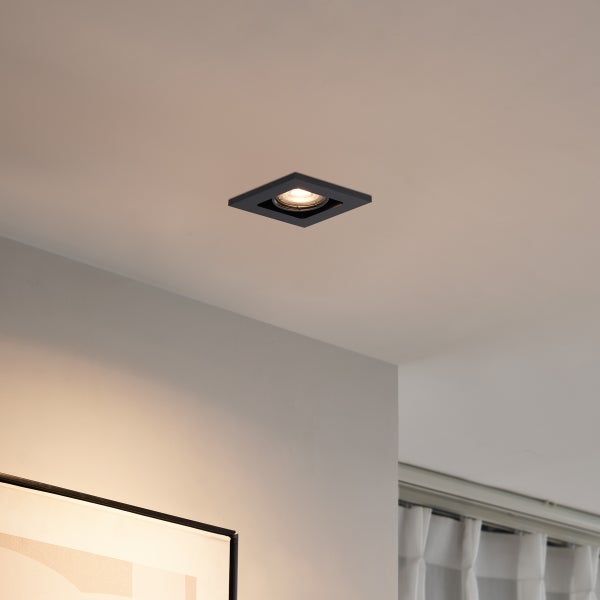 Quadratischer Einbaustrahler in Schwarz, an einer hellen Decke montiert und eingeschaltet.