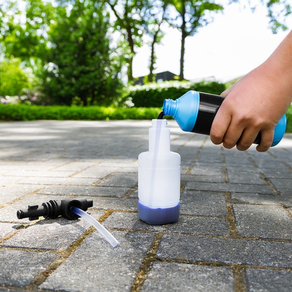 Eine Frau reinigt Steinplatten auf einer Terrasse mit einem Flächenreiniger für Hochdruckreiniger.