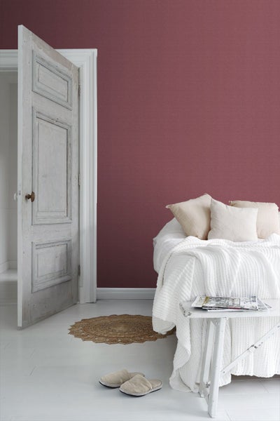 Schlafzimmer mit Bett, Tisch und geöffneter Tür vor einer gemusterten Wand