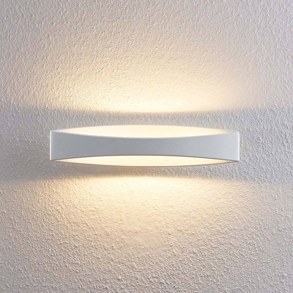 Moderne Wandleuchte in elliptischer Form mit Lichtaustritt nach oben und unten an einer strukturierten Wand.