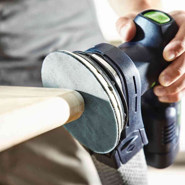 Detailansicht eines Handschleifers beim Bearbeiten eines Holzstücks.