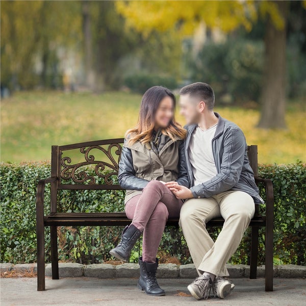 Paar sitzt auf einer Gartenbank mit verzierter Rückenlehne