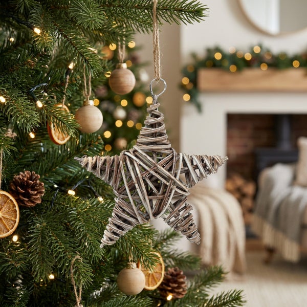Weihnachtsbaumschmuck Stern aus geflochtenem Weidenholz hängend an einem Tannenbaum im Wohnzimmer