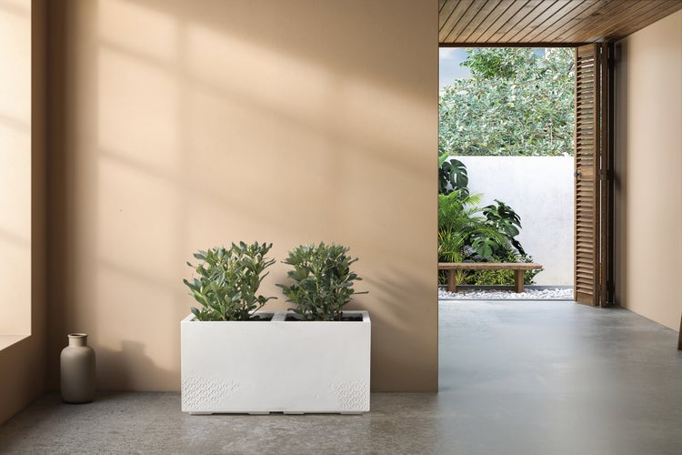 Szene mit einem weißen Pflanzkasten mit Pflanzen, einer braunen Vase und einem Blick in einen Garten mit einer Holzbank