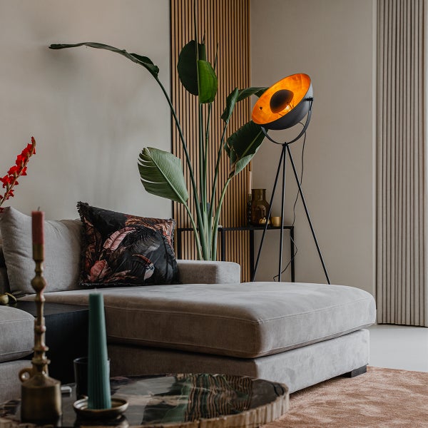 Wohnzimmer mit Sofa, Stehlampe und Zimmerpflanze vor einer Wandverkleidung aus Holzpaneelen