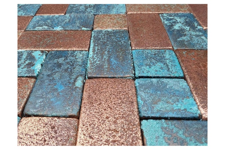Nahaufnahme von rechteckigen Pflastersteinen in blauen und kupferfarbenen Farbtönen.