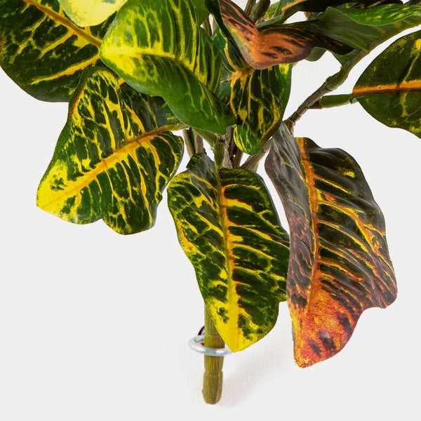 Künstliche Croton-Pflanze mit gemusterten Blättern in Grün, Gelb und Rot.