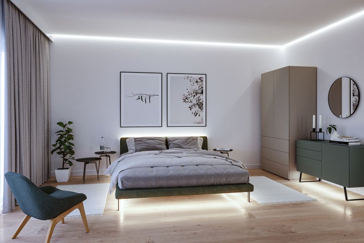 Modernes Schlafzimmer mit Polsterbett, Kleiderschrank, Sideboard und Sessel. Helle Atmosphäre durch indirekte Beleuchtung und Parkettboden.