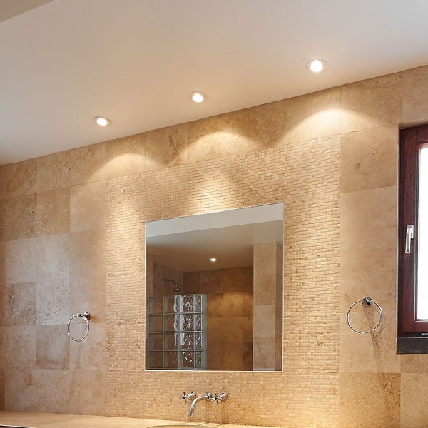 Modernes Badezimmer mit Natursteinfliesen, Spiegel mit Mosaikumrandung, drei Einbaustrahlern und Waschtischarmatur aus Chrom.