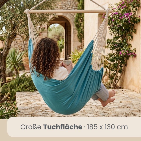 Hängesessel aus Stoff mit Holzstab in einem hellen Garten, große Tuchfläche 185 mal 130 Zentimeter.