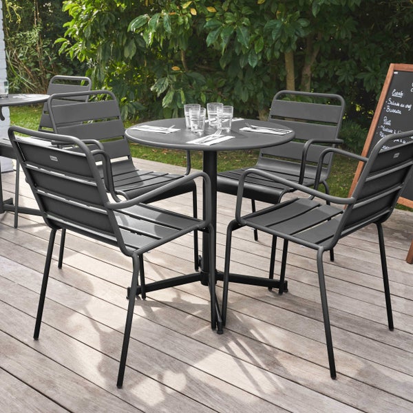 Runder Bistro-Gartentisch aus Metall auf einer Holzterrasse, gedeckt für zwei Personen vor Gartenkulisse.
