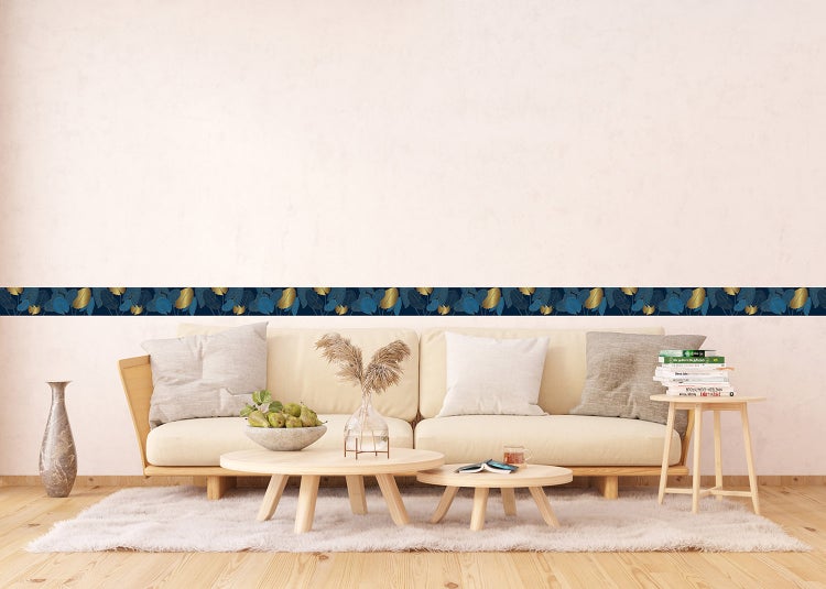 Selbstklebende Tapetenbordüre mit Blattmuster in Blau und Gold, angebracht an einer hellen Wand in einem modernen Wohnzimmer.