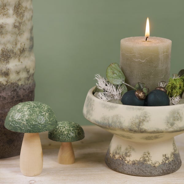 Dekorative Tischszene mit Kerze, Kerzenständer und Holzpilzen