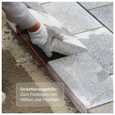 Verlegen von Terrassenplatten aus Naturstein in ein Mörtelbett unter Verwendung einer Laserlinie als Orientierungshilfe für Höhe und Flucht.