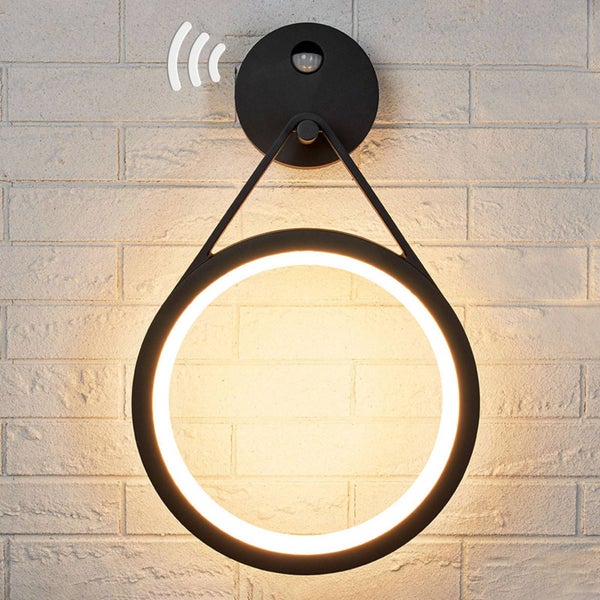 Ringförmige Wandleuchte in Schwarz mit Bewegungsmelder und warmweißem LED-Licht an einer Ziegelwand.