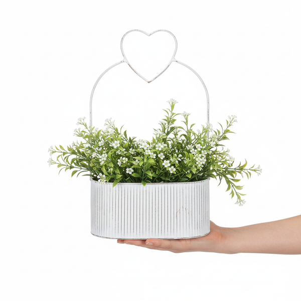 Dekorativer Pflanztopf aus geriffeltem Metall mit künstlichen Blumen und hohem Griff in Herzform.