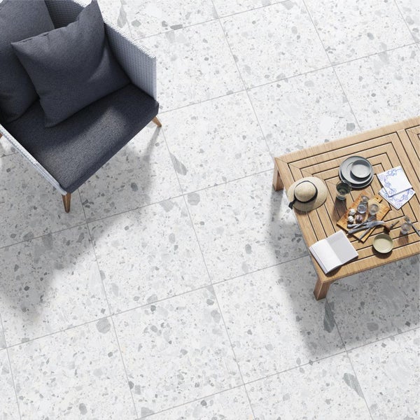 Helle Bodenfliesen mit Terrazzo-Optik, kombiniert mit Sitzgelegenheit und Holztisch für den Außenbereich