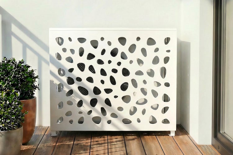 Verkleidung für eine Klimaanlage mit dekorativen Aussparungen auf einem Balkon.