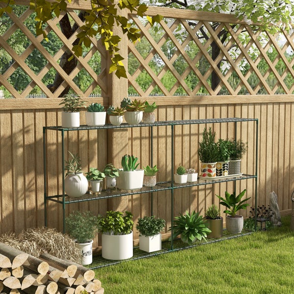 Organisiertes dreistöckiges Gartenregal aus grünem Metallgeflecht vor Holzzaun, bestückt mit Topfpflanzen und Kräutern im hellen Garten.