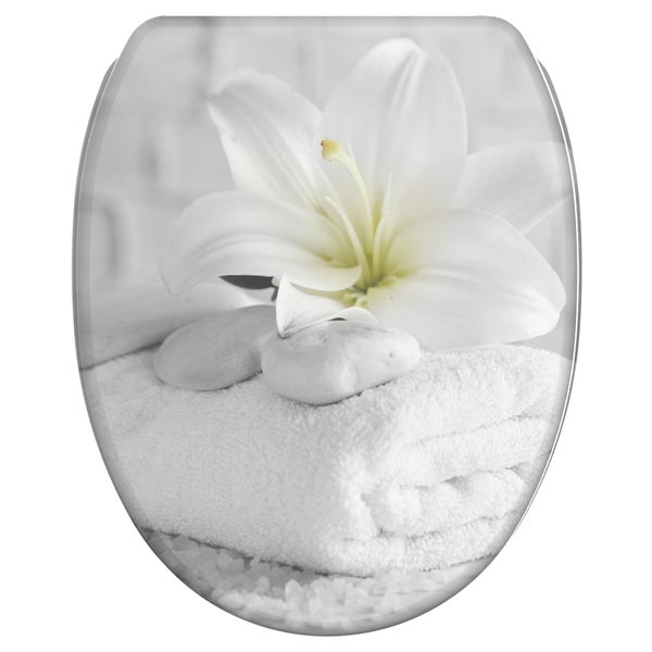 WC-Sitz mit grafischem Motiv aus weißer Lilie, glatten Steinen und einem gefalteten Handtuch.