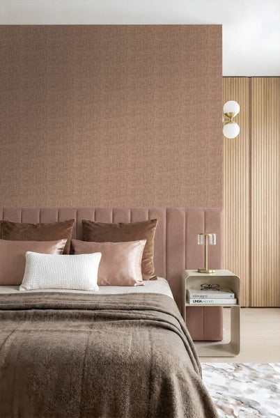 Modernes Schlafzimmer mit strukturierter Vliestapete hinter einem gepolsterten Kopfteil und einem Nachttisch mit Tischlampe.